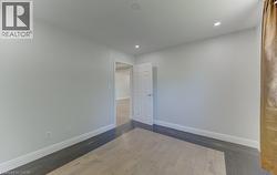 Room featuring light-toned flooring, recessed ceiling lighting, white baseboards, and a paneled door - 