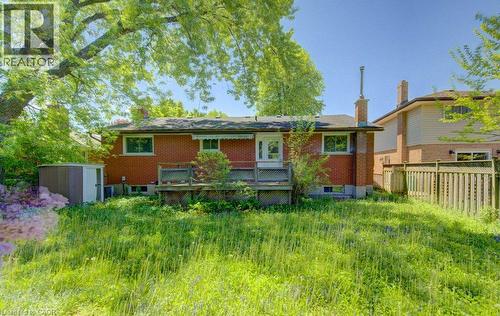 Rear brick exterior featuring an elevated deck with wood railing, white door with glass insert, and multiple windows - 80 Lower Canada Crescent, Kitchener, ON - Outdoor