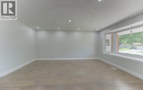 Spacious room featuring light wood-finish flooring, recessed ceiling lighting, a large bay window with white trim, and a textured ceiling detail - 80 Lower Canada Crescent, Kitchener, ON - Indoor Photo Showing Other Room