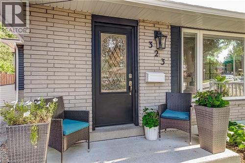 Brick exterior featuring a black front door with decorative glass, a white mailbox, and a large front window - 323 Cranbrook Drive, Hamilton, ON - Outdoor With Deck Patio Veranda With Exterior