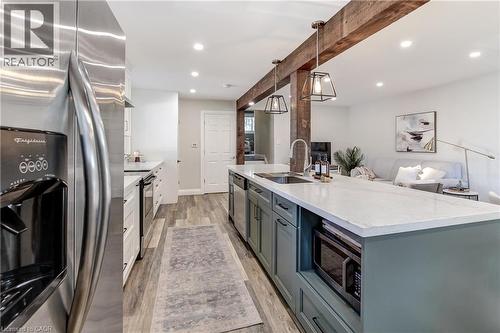 Modern kitchen with a large central island featuring a sink, integrated microwave, and pendant lighting - 323 Cranbrook Drive, Hamilton, ON - Indoor Photo Showing Kitchen With Upgraded Kitchen