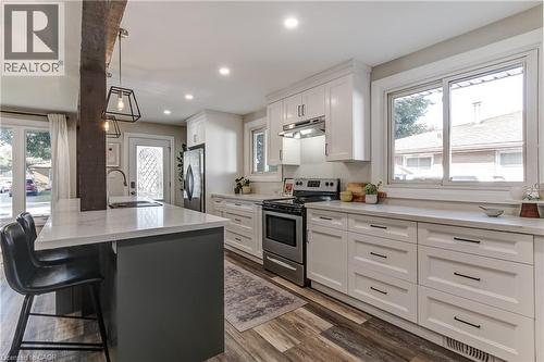 Modern kitchen featuring white shaker cabinetry, stainless steel appliances, wood-finish flooring, recessed lighting, and a kitchen island with pendant fixtures - 323 Cranbrook Drive, Hamilton, ON - Indoor Photo Showing Kitchen With Upgraded Kitchen