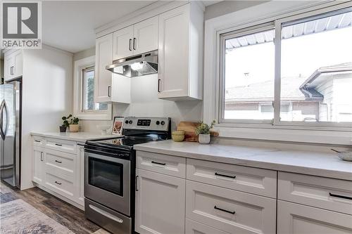 Kitchen featuring white cabinetry, stainless steel appliances, light-toned countertops, and wood-finish flooring - 323 Cranbrook Drive, Hamilton, ON - Indoor Photo Showing Kitchen