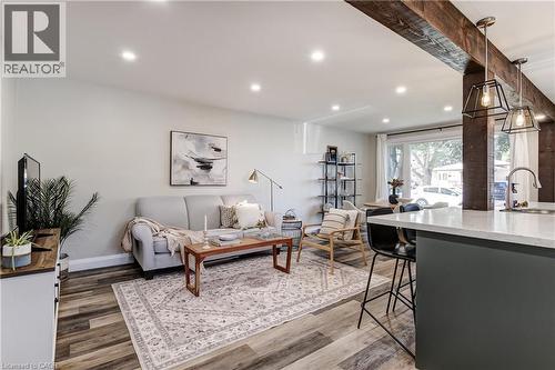 Spacious living area featuring wood-finish flooring, recessed lighting, and a large front-facing window - 323 Cranbrook Drive, Hamilton, ON - Indoor Photo Showing Living Room