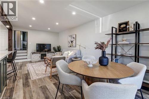 Open-concept living area with wood-finish flooring, recessed lighting, a built-in kitchen island with seating, and a prominent exposed beam detail - 323 Cranbrook Drive, Hamilton, ON - Indoor Photo Showing Dining Room