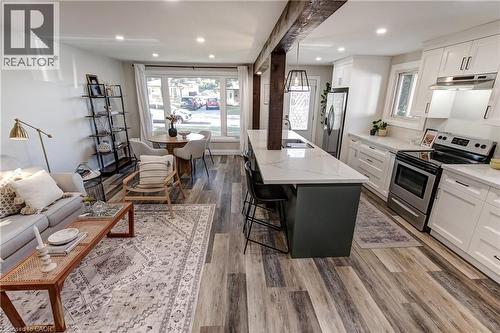 Open-concept living space featuring wood-finish flooring, recessed lighting, and a kitchen with white cabinetry - 323 Cranbrook Drive, Hamilton, ON - Indoor Photo Showing Kitchen