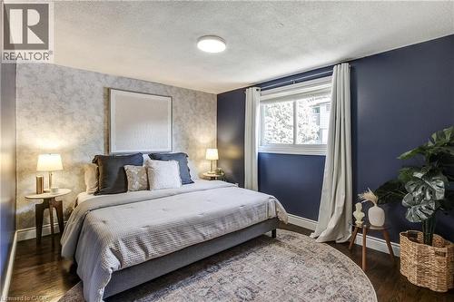 Spacious sleeping area featuring dark wood-finish flooring and a large window with white trim - 323 Cranbrook Drive, Hamilton, ON - Indoor Photo Showing Bedroom