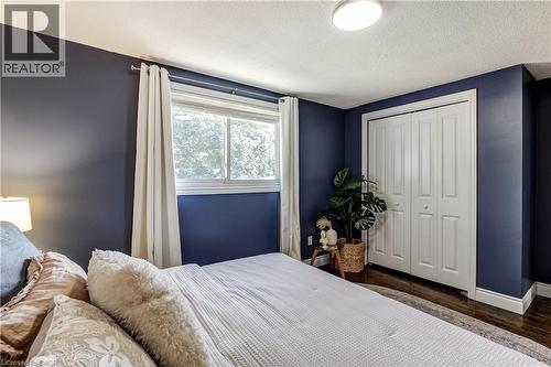 Bedroom featuring dark-toned walls, a double window with white trim, and a bi-fold closet with white panel doors - 323 Cranbrook Drive, Hamilton, ON - Indoor Photo Showing Bedroom