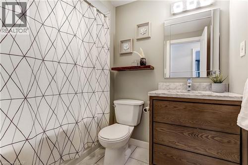 Bathroom featuring a white bathtub, wood-finish vanity with a single basin, a chrome faucet, and a rectangular mirror with integrated lighting - 323 Cranbrook Drive, Hamilton, ON - Indoor Photo Showing Bathroom
