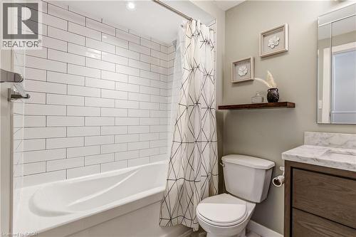 Bathroom featuring a built-in bathtub with subway tile surround, a single floating shelf, and a vanity with a white countertop and dark wood-finish cabinetry - 323 Cranbrook Drive, Hamilton, ON - Indoor Photo Showing Bathroom