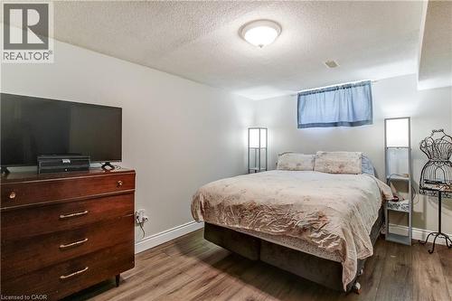 Bedroom featuring wood-finish flooring, white baseboards, and a window with curtains - 323 Cranbrook Drive, Hamilton, ON - Indoor Photo Showing Bedroom