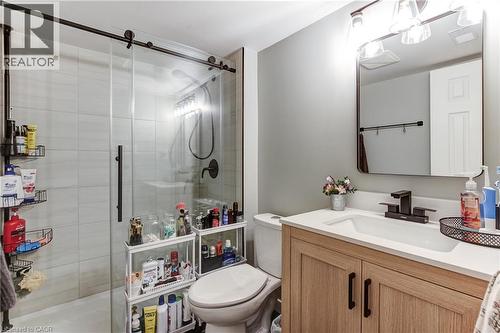 Contemporary bathroom featuring a light wood-finish vanity with a white countertop and undermount sink, matte black faucet, and a frameless mirror - 323 Cranbrook Drive, Hamilton, ON - Indoor Photo Showing Bathroom