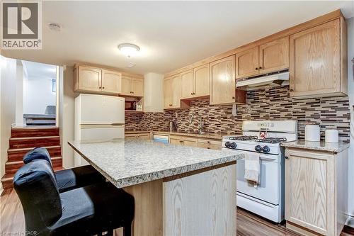 Kitchen featuring light wood cabinetry, a mosaic tile backsplash, and stone-finish countertops - 323 Cranbrook Drive, Hamilton, ON - Indoor Photo Showing Kitchen