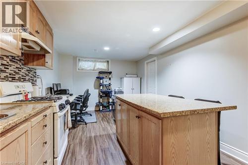 Kitchen area featuring light wood cabinetry with dark hardware, granite-finish countertops, and a mosaic tile backsplash - 323 Cranbrook Drive, Hamilton, ON - Indoor Photo Showing Kitchen
