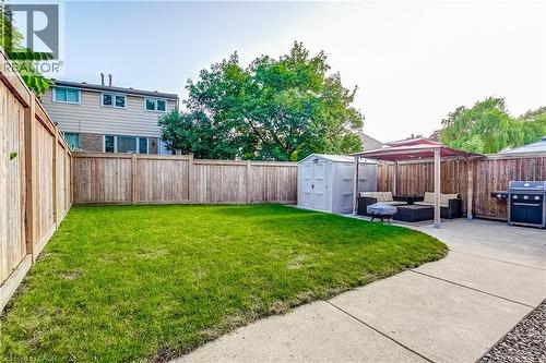 Private backyard featuring a concrete patio, a wooden privacy fence, and a manicured lawn - 323 Cranbrook Drive, Hamilton, ON - Outdoor