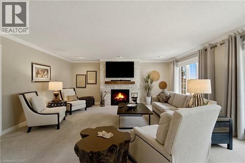 Living area featuring a floor-to-ceiling stacked stone fireplace, a wood mantel, soft wall-to-wall carpeting, crown molding, and recessed lighting - 1090 Crofton Way, Burlington, ON - Indoor Photo Showing Living Room With Fireplace