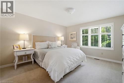 Carpeted room featuring a large window with white plantation shutters, a rattan headboard, and recessed ceiling lighting - 1090 Crofton Way, Burlington, ON - Indoor Photo Showing Bedroom