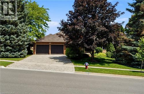 Brick exterior home featuring a two-car garage with dark paneled doors - 1090 Crofton Way, Burlington, ON - Outdoor