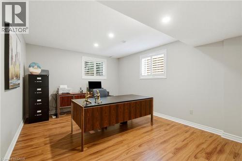 Versatile room featuring wood-finish flooring, recessed lighting, and a window with white plantation shutters - 1090 Crofton Way, Burlington, ON - Indoor
