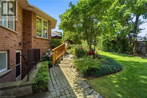 Mature landscaping framing a brick exterior with a stone paver pathway - 1090 Crofton Way, Burlington, ON - Outdoor