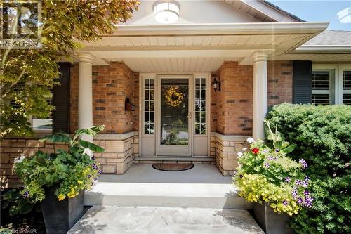 Brick and stone facade featuring a covered entry, fluted columns, an overhead light fixture, and a glass-paneled entry door - 1090 Crofton Way, Burlington, ON - Outdoor