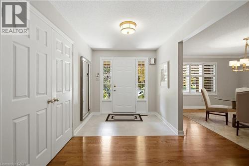 Entryway featuring a white paneled door with sidelight windows, a flush mount ceiling light, light-toned tile flooring, and wood-finish flooring - 1090 Crofton Way, Burlington, ON - Indoor Photo Showing Other Room
