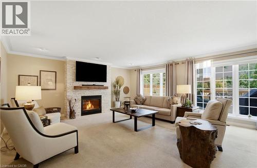 Living room featuring a stacked stone fireplace with a wood mantle, recessed lighting, crown molding, and large windows with grid patterns - 1090 Crofton Way, Burlington, ON - Indoor Photo Showing Living Room With Fireplace