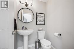 Modern bathroom featuring a pedestal sink, round wall-mounted mirror, and contemporary vanity lighting - 