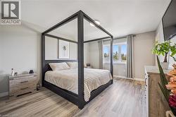 Bedroom featuring light gray walls, wood-finish flooring, two windows with vertical blinds, and a flush mount ceiling light - 