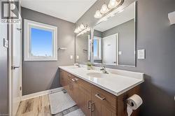 Contemporary bathroom featuring a double vanity with wood-finish cabinetry, white countertop, dual undermount sinks, and an expansive wall mirror - 