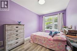 Bright room featuring a large window with white trim, wood-finish flooring, and a flush mount ceiling light - 