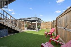 Backyard featuring artificial turf, a wood fence, and a gazebo with a paved area - 