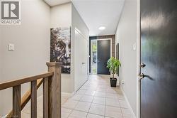 Entryway featuring light-toned tile flooring, a solid wood staircase railing, and a dark-paneled accent wall - 