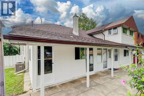 Expansive back patio featuring a covered area with support columns, multiple glass-paned doors, and exterior lighting fixtures - 182 Avalon Place, Kitchener, ON - Outdoor