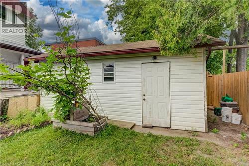 Detached shed featuring white vinyl siding, a brown shingle roof, and a wood entry door - 182 Avalon Place, Kitchener, ON - Outdoor With Exterior