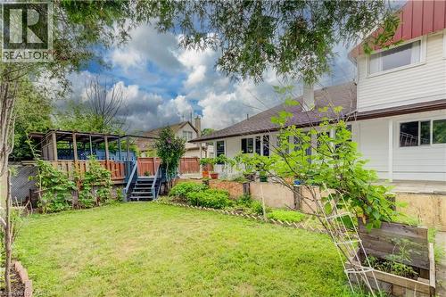 Expansive lawn area with a raised wooden deck featuring a pergola structure and steps - 182 Avalon Place, Kitchener, ON - Outdoor