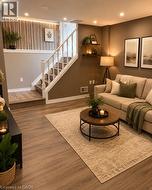 Lower-level living area featuring wood-finish flooring, recessed lighting, and a white balustrade staircase - 