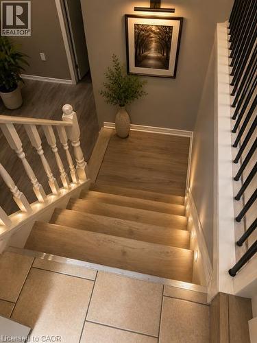 Staircase featuring wood-finish treads with integrated step lighting and a white baluster railing - 143 Grenfell Place, London, ON - Indoor Photo Showing Other Room