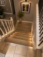 Staircase featuring wood-finish treads with integrated step lighting and a white baluster railing - 