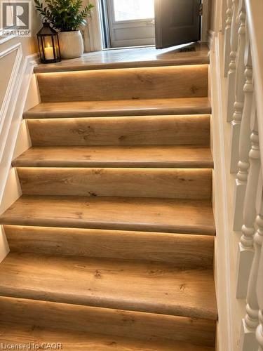 Staircase featuring wood-finish treads with integrated strip lighting, white risers, and a white baluster railing - 143 Grenfell Place, London, ON - Indoor Photo Showing Other Room