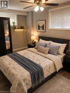 Spacious bedroom featuring wood-finish flooring, a ceiling fan with integrated lighting, and a built-in illuminated shelf - 