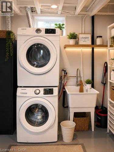 Dedicated laundry area featuring stacked appliances, a utility sink with a high-arc faucet, and an exposed beam ceiling - 143 Grenfell Place, London, ON - Indoor Photo Showing Laundry Room