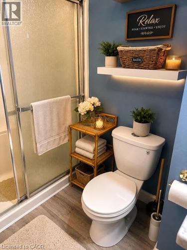 Full bathroom with wood-finish flooring, a white toilet, and a frosted glass shower enclosure - 143 Grenfell Place, London, ON - Indoor Photo Showing Bathroom