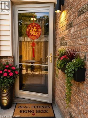Entryway featuring a storm door with a brass handle, brick exterior siding, and a wall-mounted exterior light fixture - 143 Grenfell Place, London, ON - 