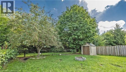 Expansive backyard featuring a manicured lawn, established trees, and a stone-lined fire pit - 143 Grenfell Place, London, ON - Outdoor