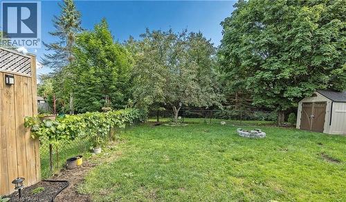 Expansive backyard featuring a manicured lawn, mature trees, and a stone fire pit - 143 Grenfell Place, London, ON - Outdoor