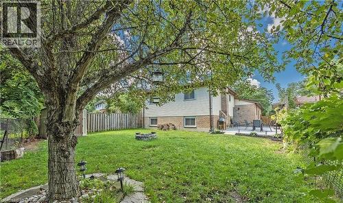 Expansive backyard featuring a mature tree, manicured lawn, and a stone fire pit - 143 Grenfell Place, London, ON - Outdoor