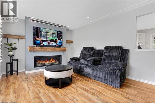 Living area featuring a built-in fireplace with a wood mantel, wood-finish flooring, recessed lighting, and a partial wall opening - 744 Birchwood Avenue, Cambridge, ON - Indoor Photo Showing Living Room With Fireplace