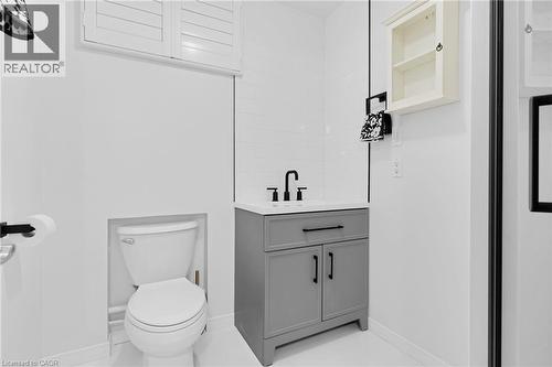 Contemporary bathroom featuring a white tile wall, a gray vanity with a white countertop, a black faucet, and a toilet - 744 Birchwood Avenue, Cambridge, ON - Indoor Photo Showing Bathroom