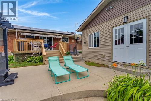 Concrete patio area featuring a brick main residence with a wooden deck and a separate structure with vinyl siding and French doors - 744 Birchwood Avenue, Cambridge, ON - Outdoor With Deck Patio Veranda With Exterior